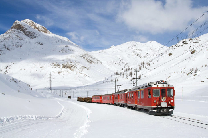 Met de trein op skivakantie: een rode trein tussen de witte bergen - een bekend beeld in de Alpen.