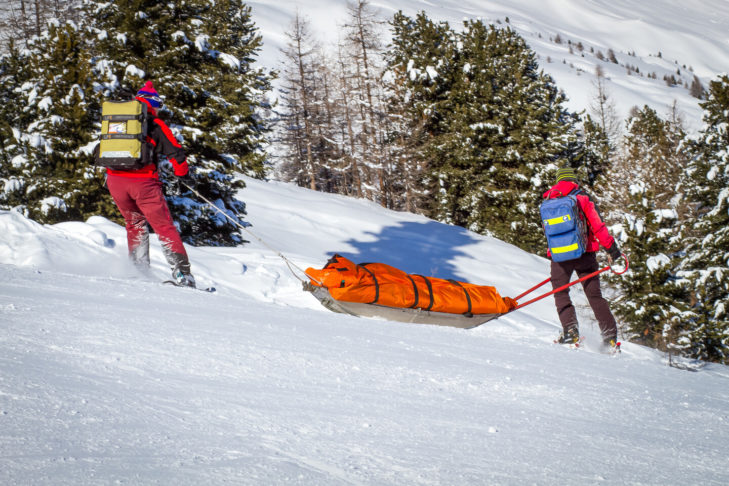 De bergredders staan altijd klaar om gewonde wintersporters te helpen na een val op de piste