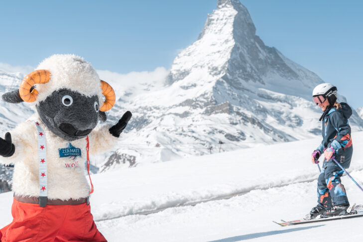 Mit Blick auf das weltbekannte Matterhorn können Kinder im Skigebiet Zermatt kostenlos Skifahren und vielleicht Maskottchen Wolli auf der Piste treffen.
