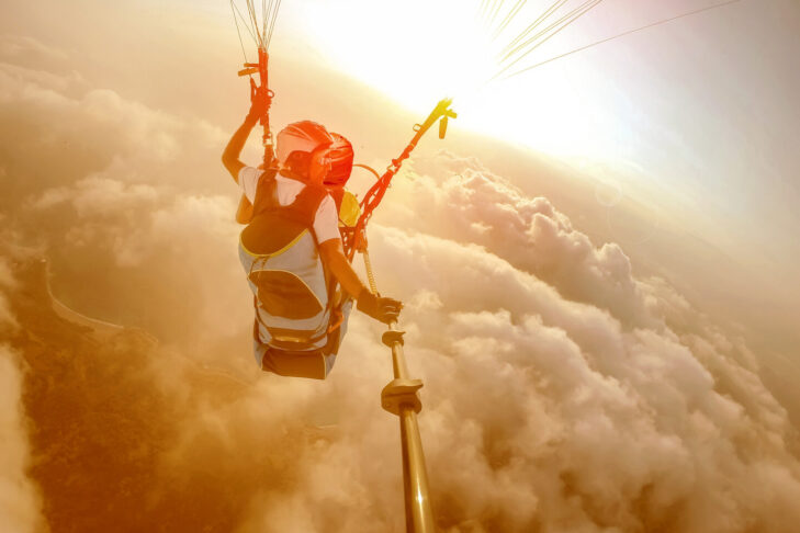 Ein Tandemflug ist der beste Einstieg für Anfänger, wenn es um Paragliding geht. Damit die Co-Piloten den Flug genießen können, ist es meist der Pilot, der die Kontrolle über den Gleitschirm hat und die Erinnerungsfotos macht.